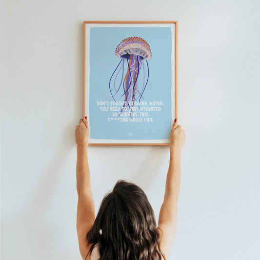 A lifestyle shot of a woman holding up a framed A3 size print to showcase its scale and visual impact in a real space.