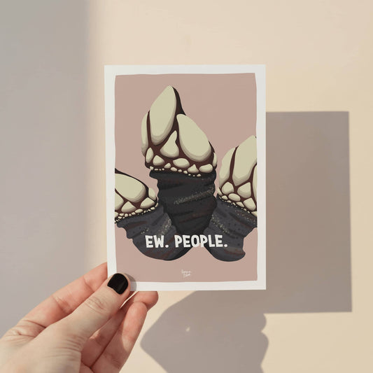 A hand holding an A6 mini print featuring an illustrated goose barnacle on a warm beige background with the quote "Ew. People." in bold dark text, displayed against a smooth sabd background by Normablok.