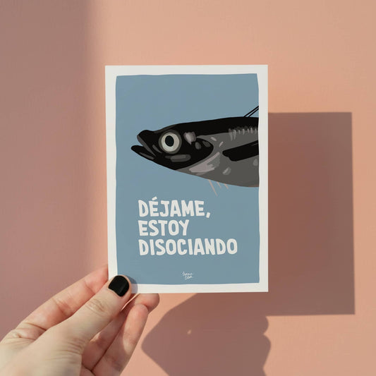 Mano sosteniendo una mini lámina A6 de la sardina disociando para mostrar el tamaño real del producto.