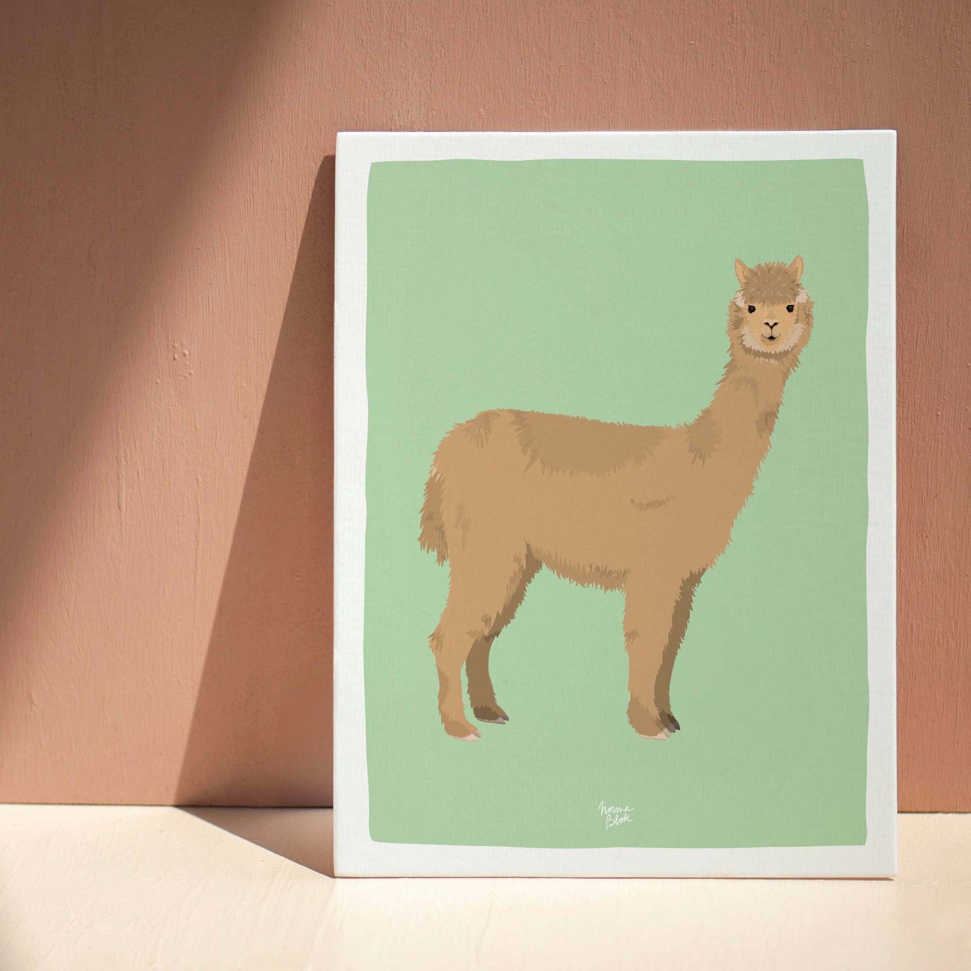 The alpaca art print elegantly leaning against a deep brown wall on a neutral beige floor. This interior styling photo shows how the warm earth tones of the alpaca illustration harmonize with a sophisticated, earthy home decor palette.