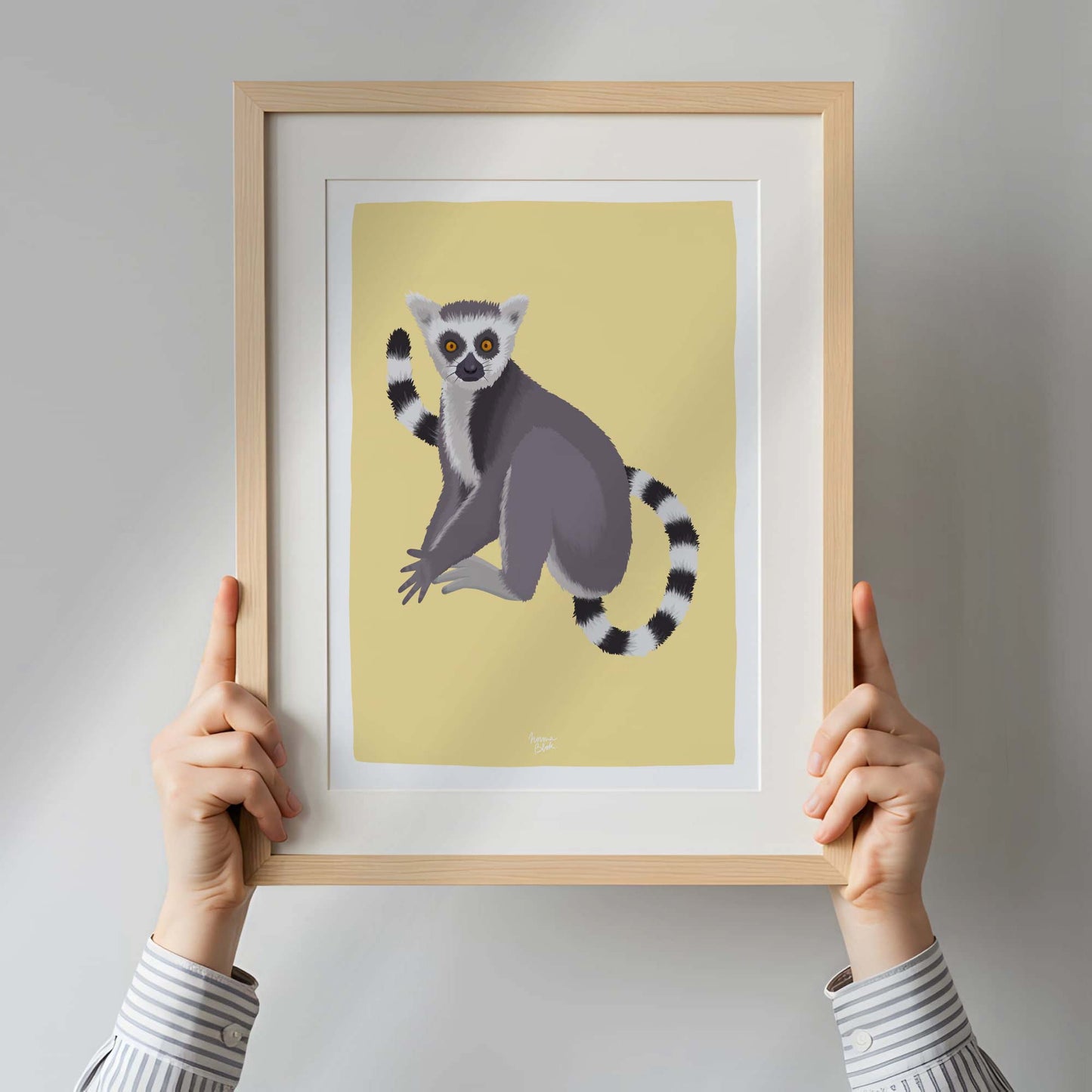 A woman holding a framed lemur art print inside a bright, modern apartment. This real-life perspective provides a clear sense of scale and demonstrates how this piece of wildlife art can serve as an eye-catching focal point in contemporary interior design.