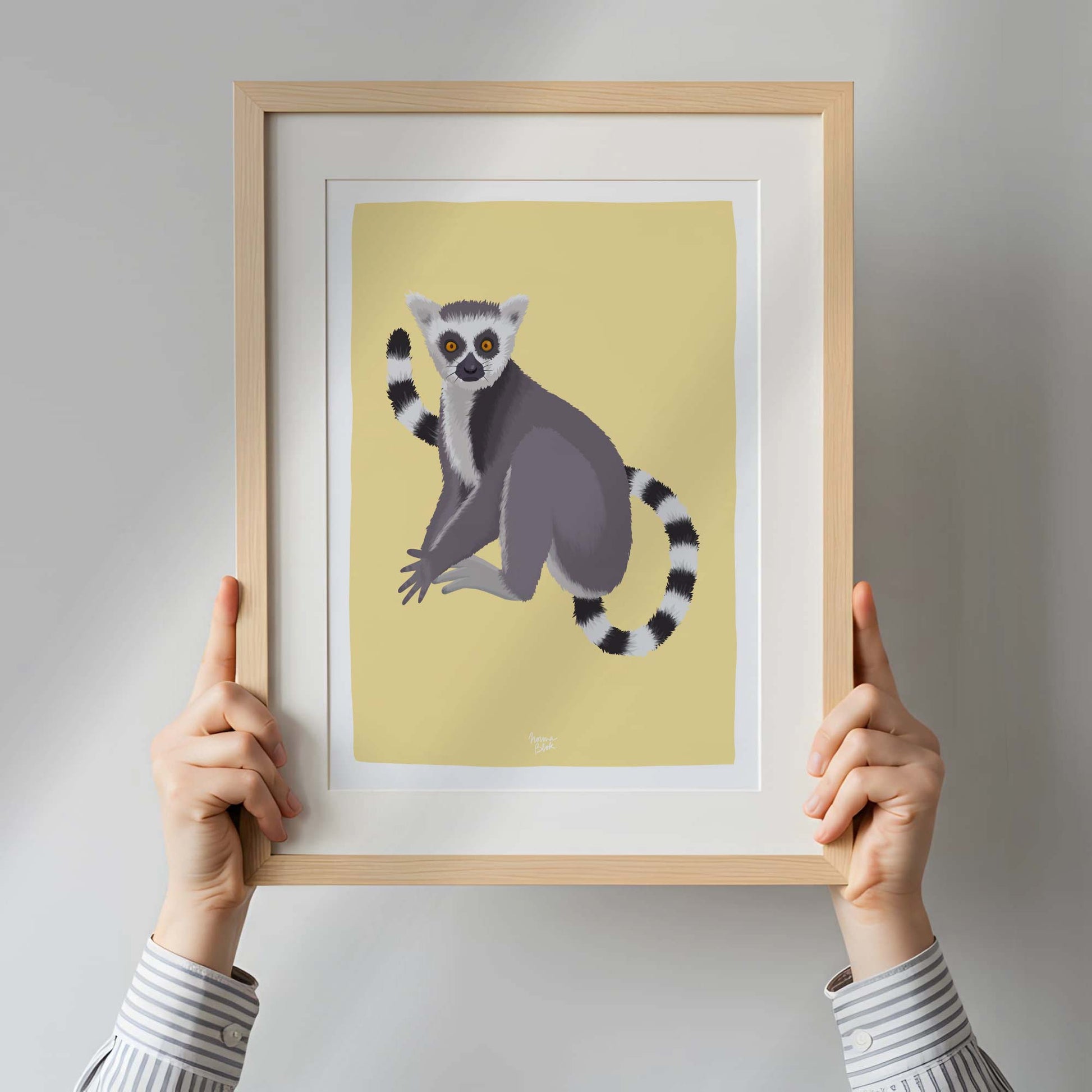 A woman holding a framed lemur art print inside a bright, modern apartment. This real-life perspective provides a clear sense of scale and demonstrates how this piece of wildlife art can serve as an eye-catching focal point in contemporary interior design.
