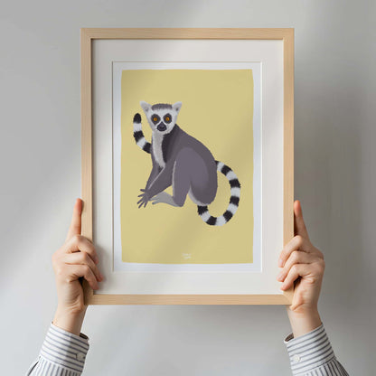 A woman holding a framed lemur art print inside a bright, modern apartment. This real-life perspective provides a clear sense of scale and demonstrates how this piece of wildlife art can serve as an eye-catching focal point in contemporary interior design.