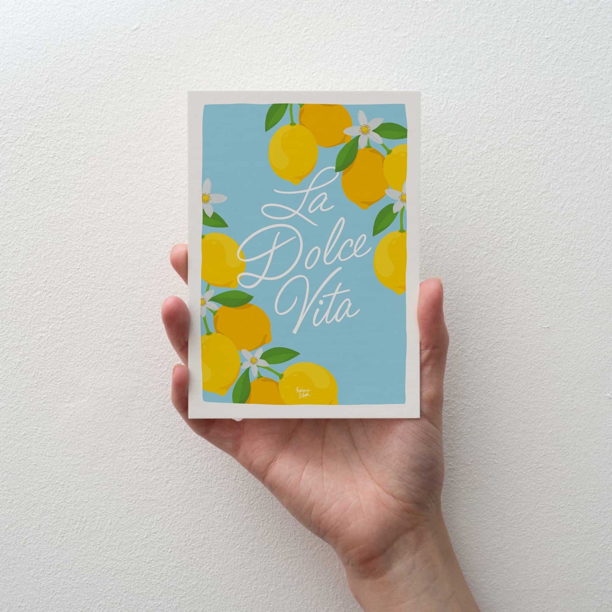 hand holding la dolce vita italian quote mini print showing white border and sky blue colors by normablok