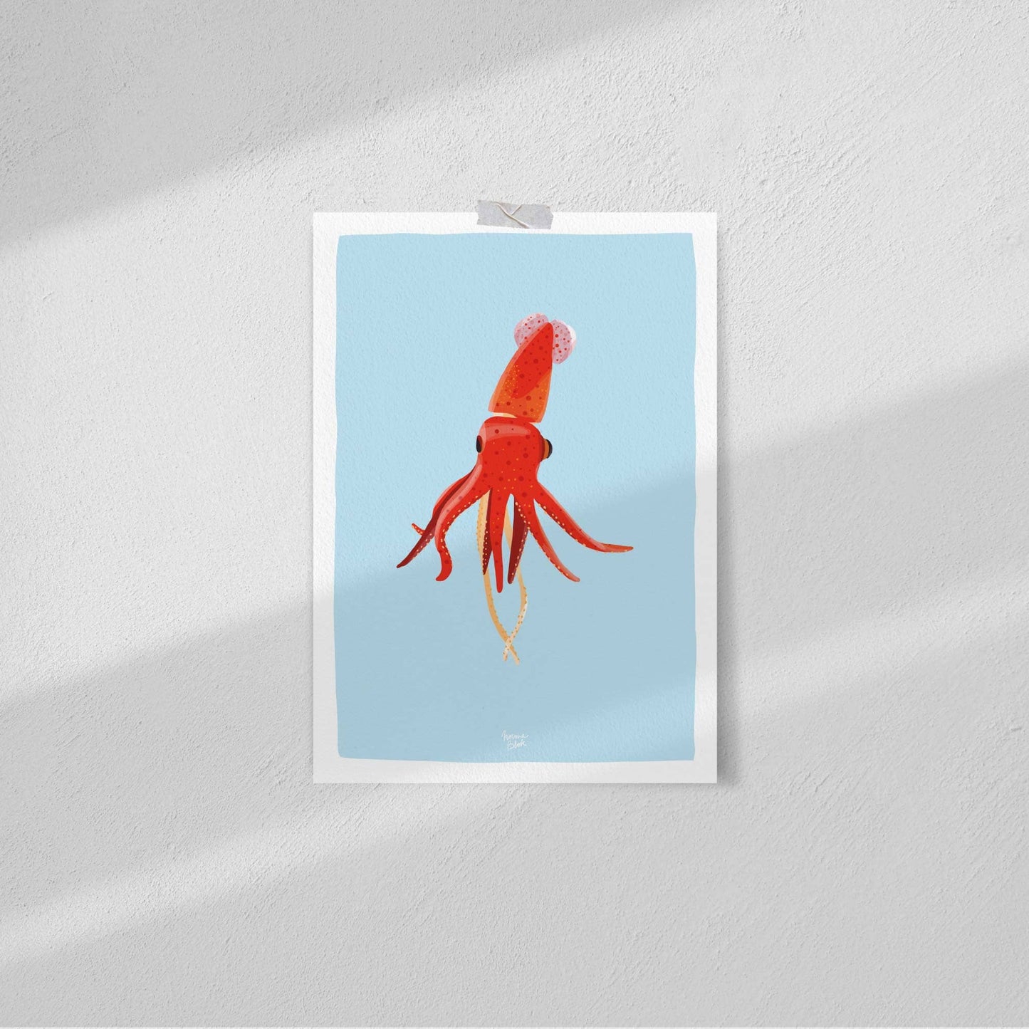 Squid art print attached to a plain white wall using clear tape, showcasing a minimalist and casual approach to hanging wall art.