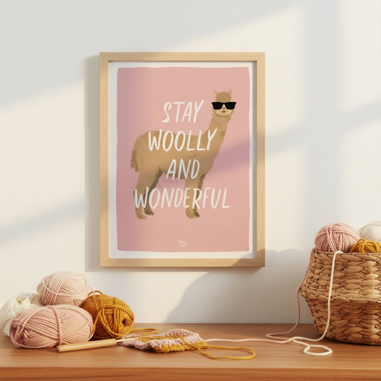The alpaca art print in a modern frame, styled inside a creative craft room. It sits on a shelf surrounded by colorful yarn balls, knitting needles, and textile tools, showing how this humorous print adds personality and a modern touch to a dedicated sewing space.