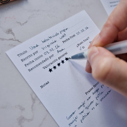 Four different reading log cards spread out on a desk, showing both the illustrated fronts and the functional tracking backs by Normablok.
