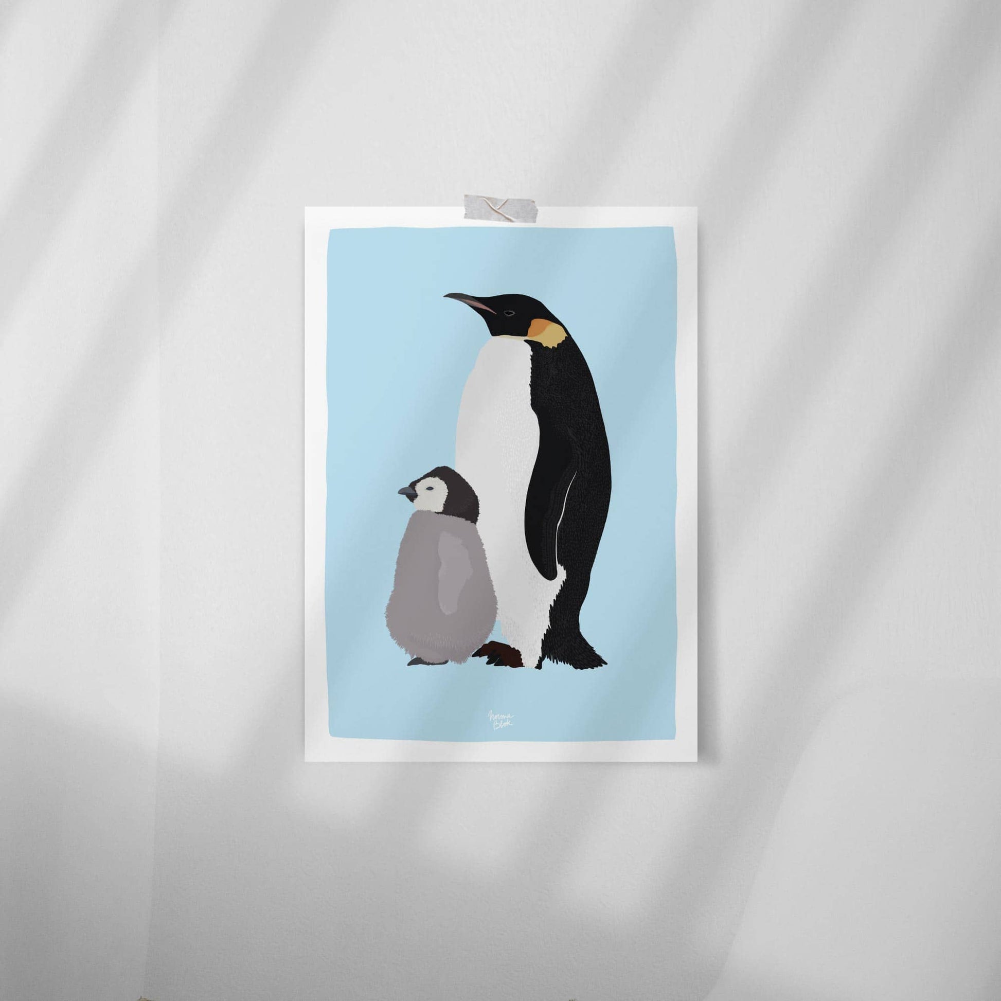 Minimalist Emperor penguin and chick art print attached with clear tape to a clean white wall. Simple and modern room decor.