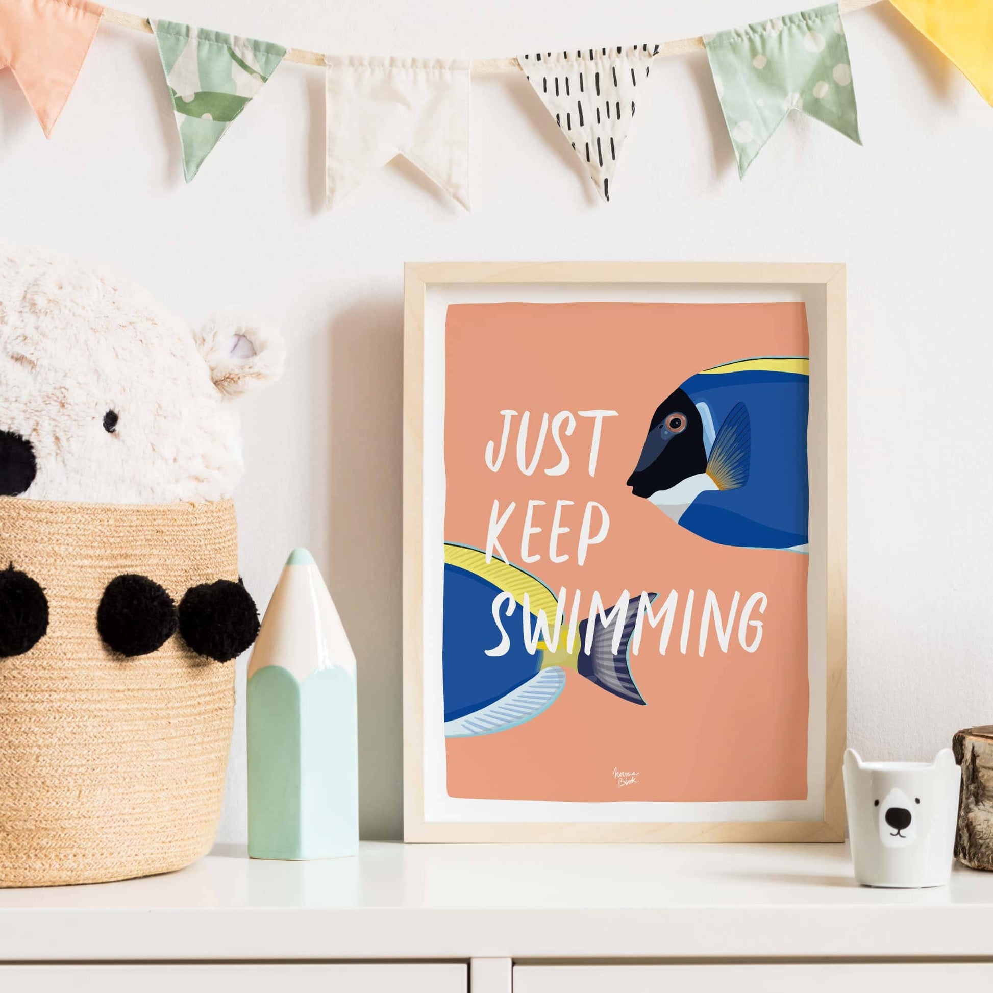 The fish art print in a minimalist black frame hanging inside a contemporary living room. It sits above a wooden shelf next to a green potted plant, showing how this humorous and colorful design brings energy and a modern touch to a home workspace.