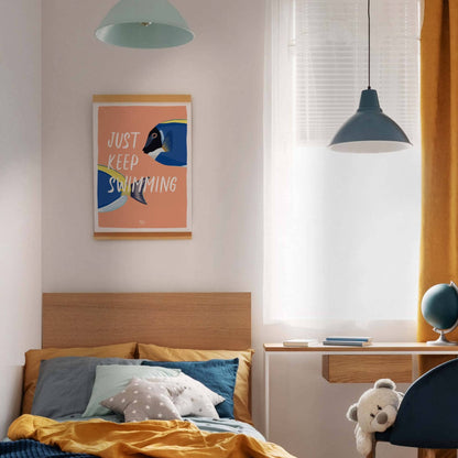 The coral "Just Keep Swimming" fish art print in a modern frame, hanging centered above the headboard of a bed in a bright kids' bedroom with clean white walls. The bedding features a mix of blue and yellow tones, creating a vibrant, fresh, and modern color contrast with the artwork.