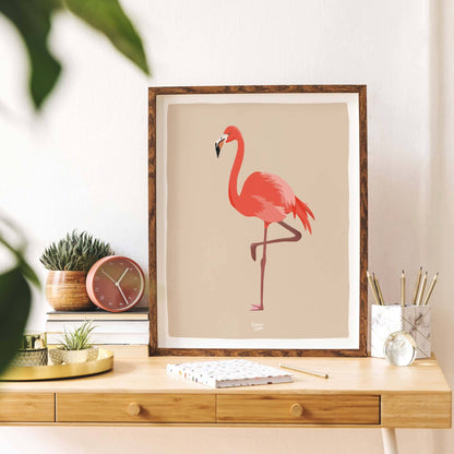 Flamingo print in a dark wooden frame, leaning on a wooden desk. View of how the print sits in a workspace.
