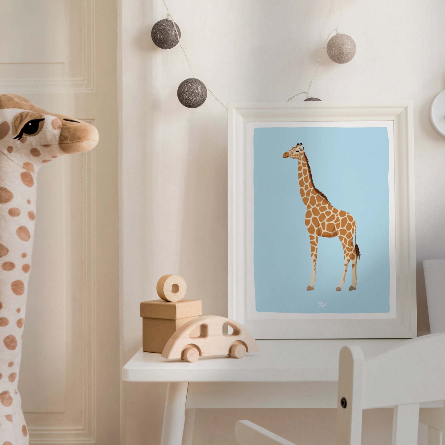 The reticulated giraffe art print in a sleek white frame within a cozy, modern nursery. Styled with a cute plush giraffe toy, this kids' room decor shows how wildlife illustrations create a playful, educational, and aesthetic environment for children.