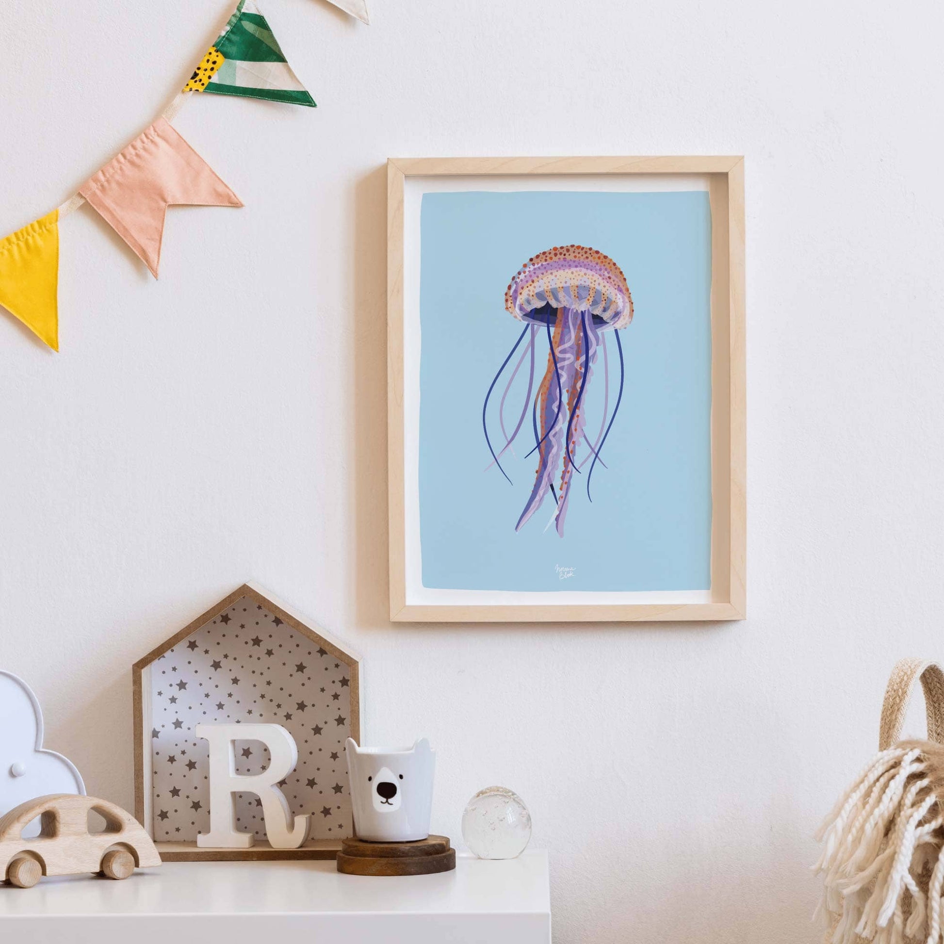 The jellyfish art print in a clean frame, styled as part of a cozy kids' room decor. The vibrant colors and gentle marine theme make it a perfect, playful addition to a child’s bedroom or nursery wall.