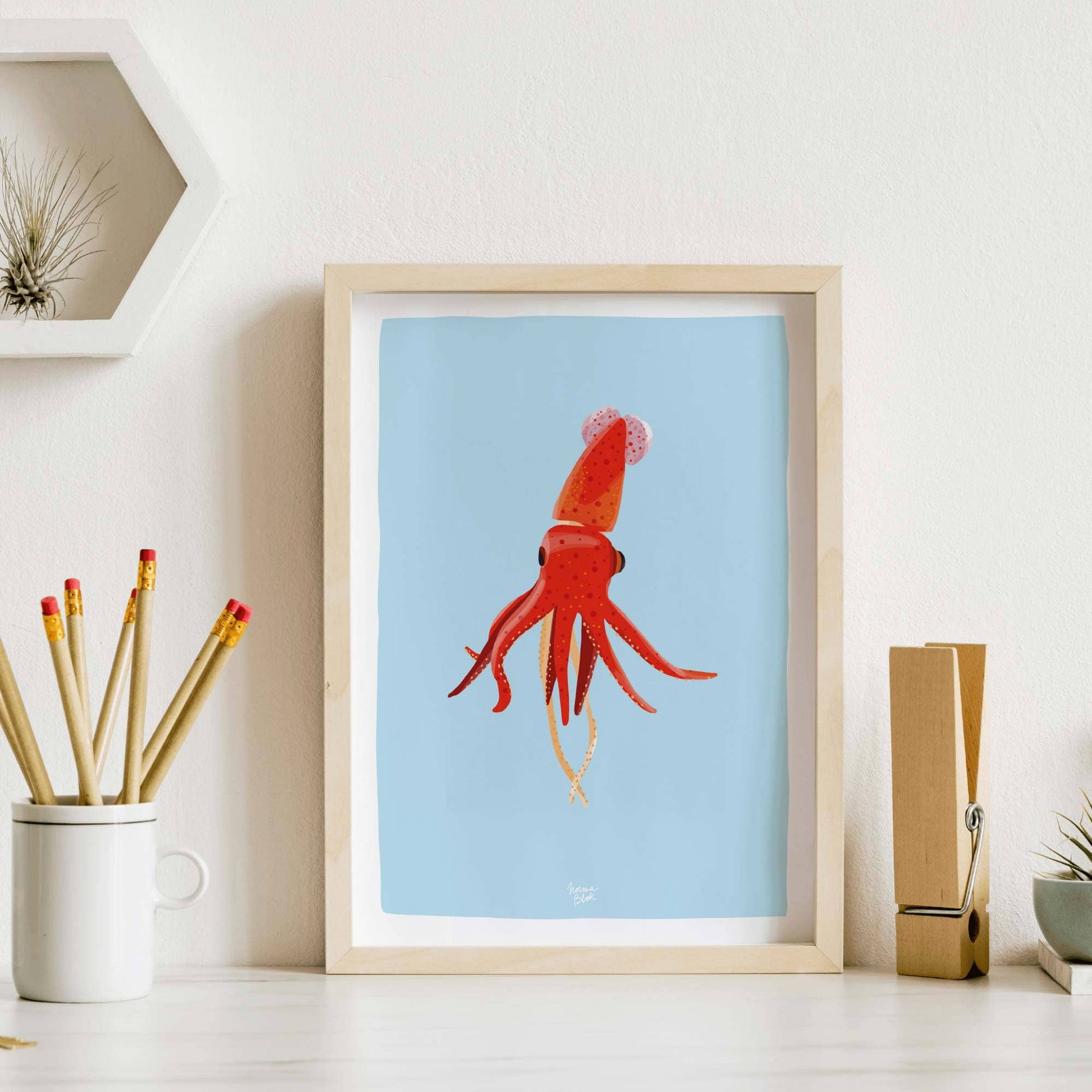 Squid art print framed and placed on a desk next to a pencil holder, demonstrating an example of office wall decor and workspace styling.