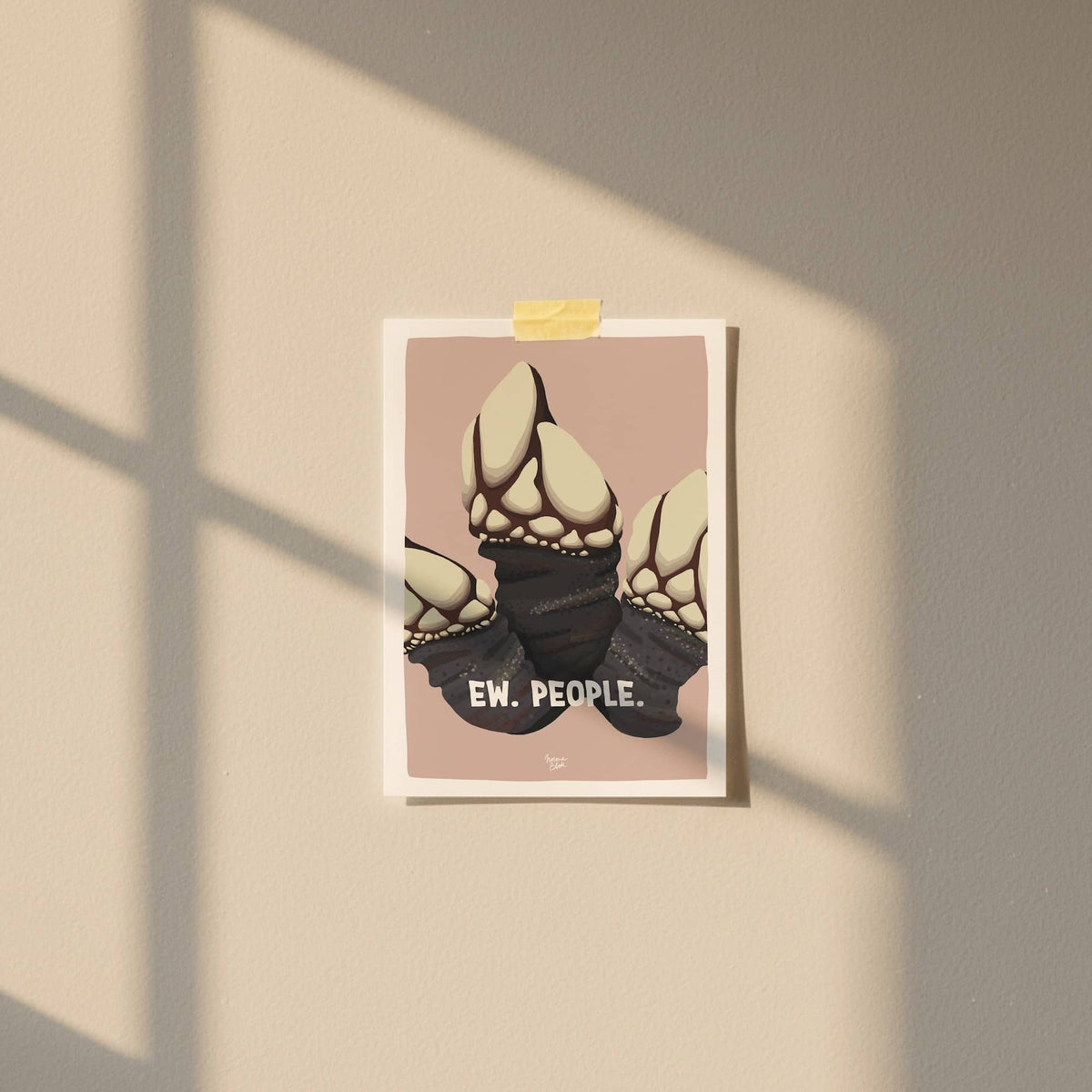 An A6 "Ew. People." barnacle mini print taped with patterned washitape to a warm salmon pink wall in a cozy room with soft natural lighting by Normablok.