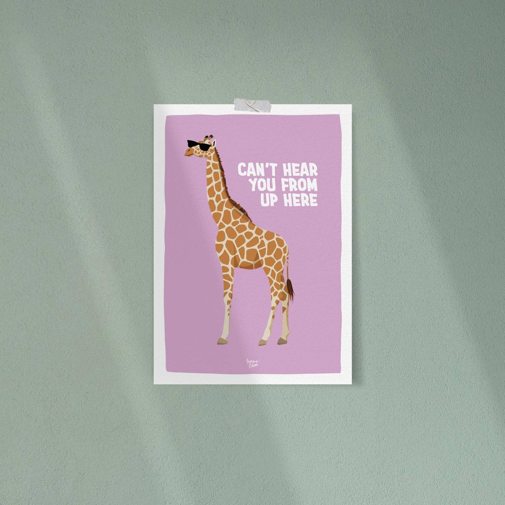 The funny giraffe art print casually attached to a solid dark green wall using strips of clear tape on the corners. The strong color contrast between the lilac background and the green wall creates a bold, effortless, and very informal office or room decoration style.
