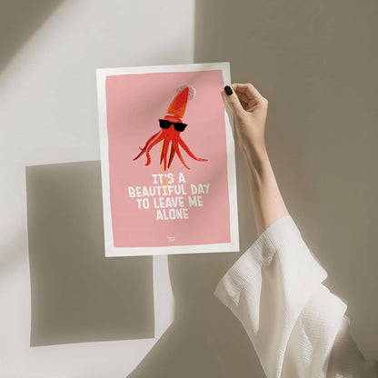 A hand holding the A4 size squid art print against a clean white background with a soft wall shadow by Normablok.