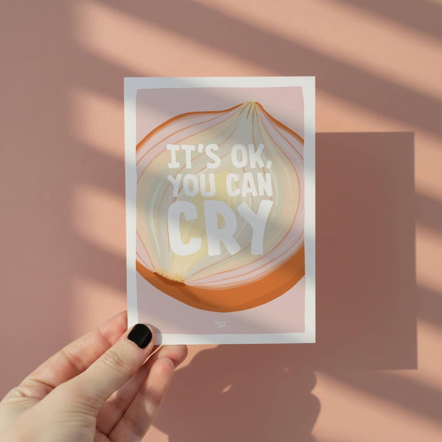 A hand holding the A6 onion pun card to showcase its size and the vibrant yet soft pink tones, perfect for a supportive greeting card by normablok.