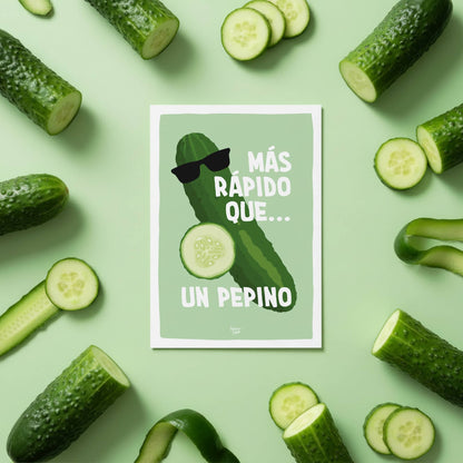 Vista cenital de la mini lámina "más rápido que un pepino" colocada en el centro de una mesa y rodeada de pepinos reales, destacando el divertido detalle de las gafas de sol en el diseño ilustrado por normablok.