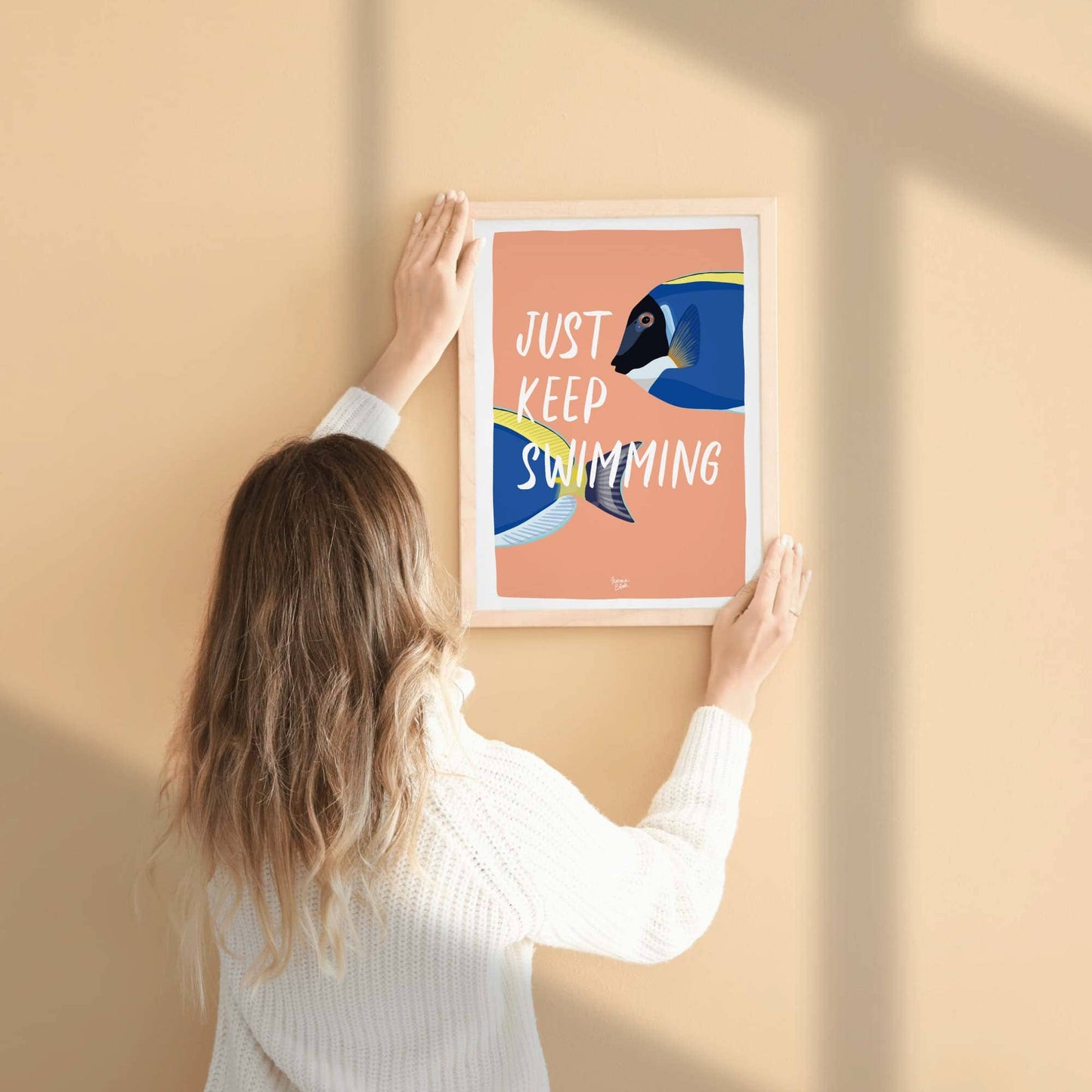 A close-up shot of a person's hand holding the printed fish illustration, providing a real-life physical reference for the scale, matte paper quality, and vibrant coral color finish. This perspective helps customers visualize the print size easily.
