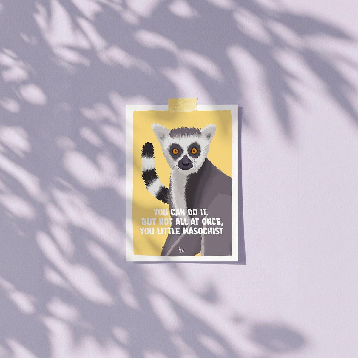 An A6 mini art print featuring the hilarious "You can do it. But not all at once, you little masochist." lemur illustration taped casually to a wall using colorful patterned washitape. The image highlights how quick and easy it is to hang or display this unframed postcard on a home office wall, workspace, or bedroom cubicle without damaging the paper or wall by Normablok.