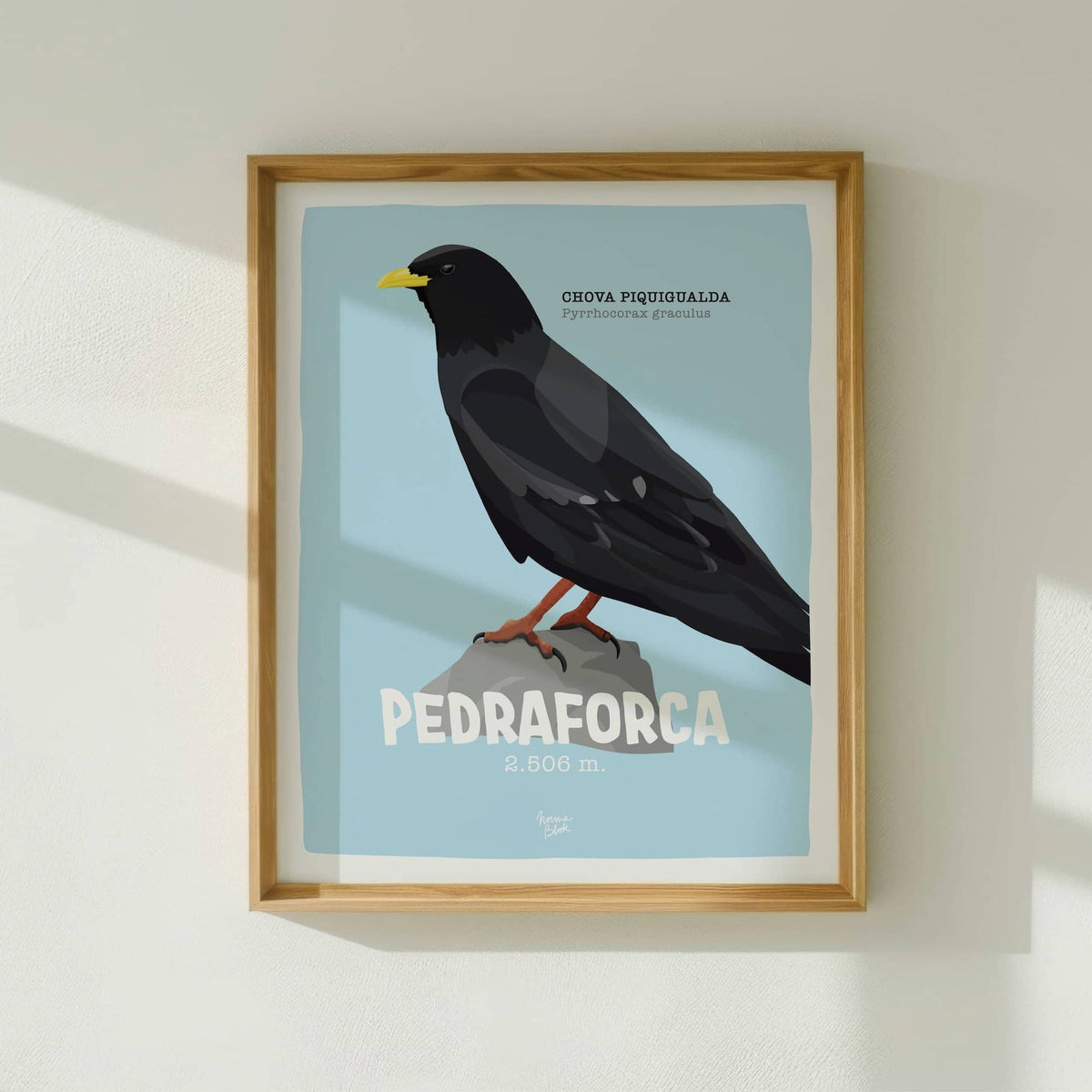 La lámina del Pedraforca enmarcada en madera clara y colocada en una pared blanca con sombras suaves de Normablok.