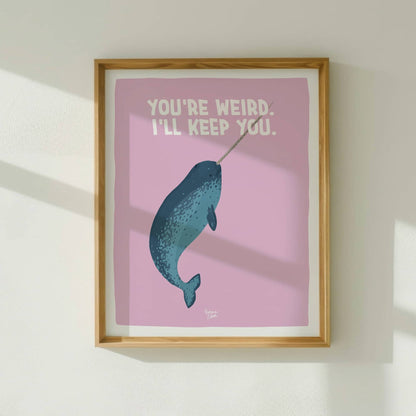 The quirky narwhal art print framed in light wood, hanging on a white wall with natural window light by Normablok.