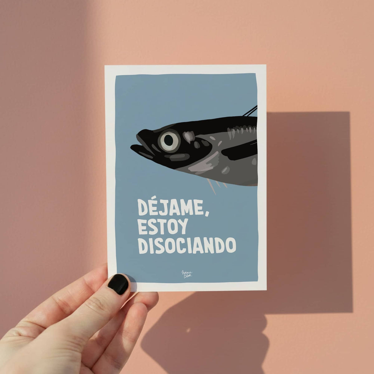 Mano sosteniendo una mini lámina A6 de la sardina disociando para mostrar el tamaño real del producto.