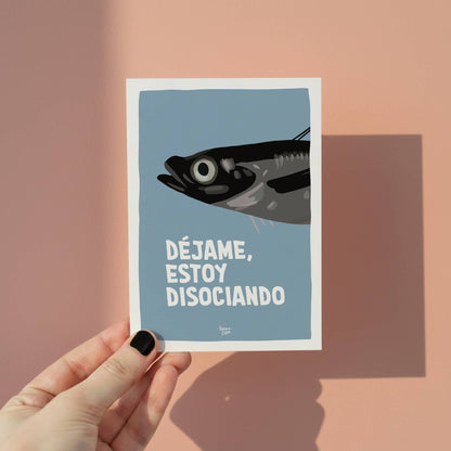 Mano sosteniendo una mini lámina A6 de la sardina disociando para mostrar el tamaño real del producto.