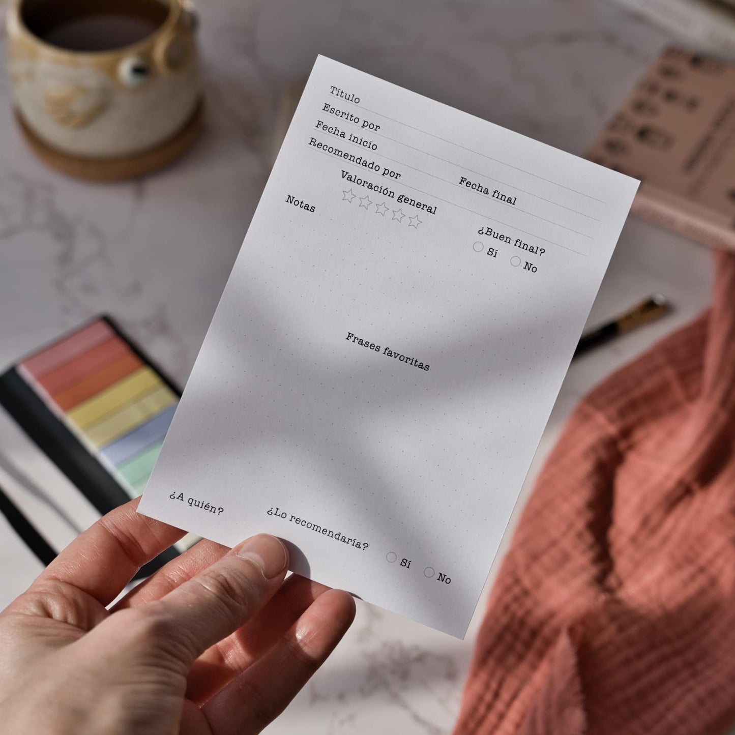 Tarjetas de seguimiento de lectura tamaño A6 utilizadas como marcapáginas dentro de una novela, que muestran cómo ayudan a los lectores a recordar lo que han leído, por Normablok.