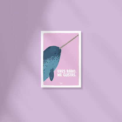 Mini lámina A6 de la cabecita de un narval sobre fondo lila claro con la frase "eres raro, me gustas" encima de una superficie de color.