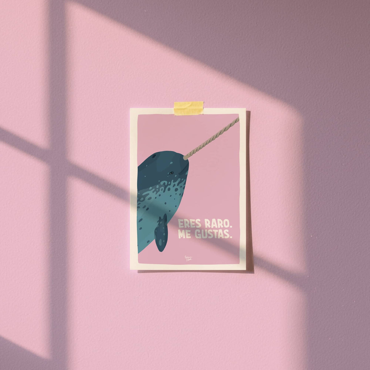 Mini lámina A6 con una ilustración de narval fijada a la pared con cinta washi tape en una habitación.
