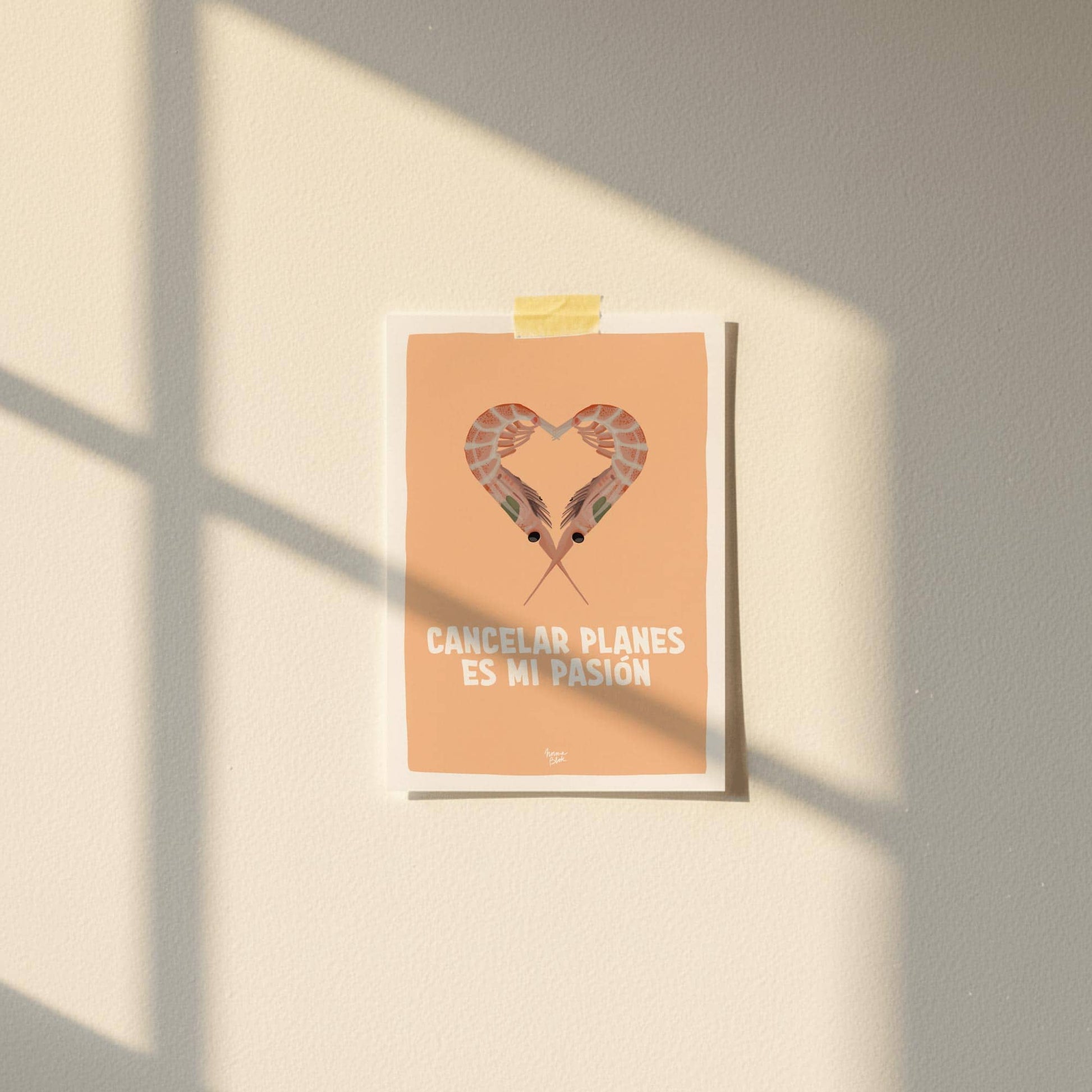 Primer plano de la postal 'cancelar planes es mi pasión' de Normablok adherida a una pared blanca lisa mediante un trozo de celo decorativo washi tape en la parte superior central. La postal destaca por su fondo naranja brillante y su ilustración de gambas en forma de corazón en un entorno de decoración minimalista.