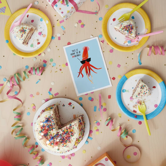 The "inkcredible" squid mini print placed next to a birthday gift and some party confetti to show its use as a fun invitation by Normablok.