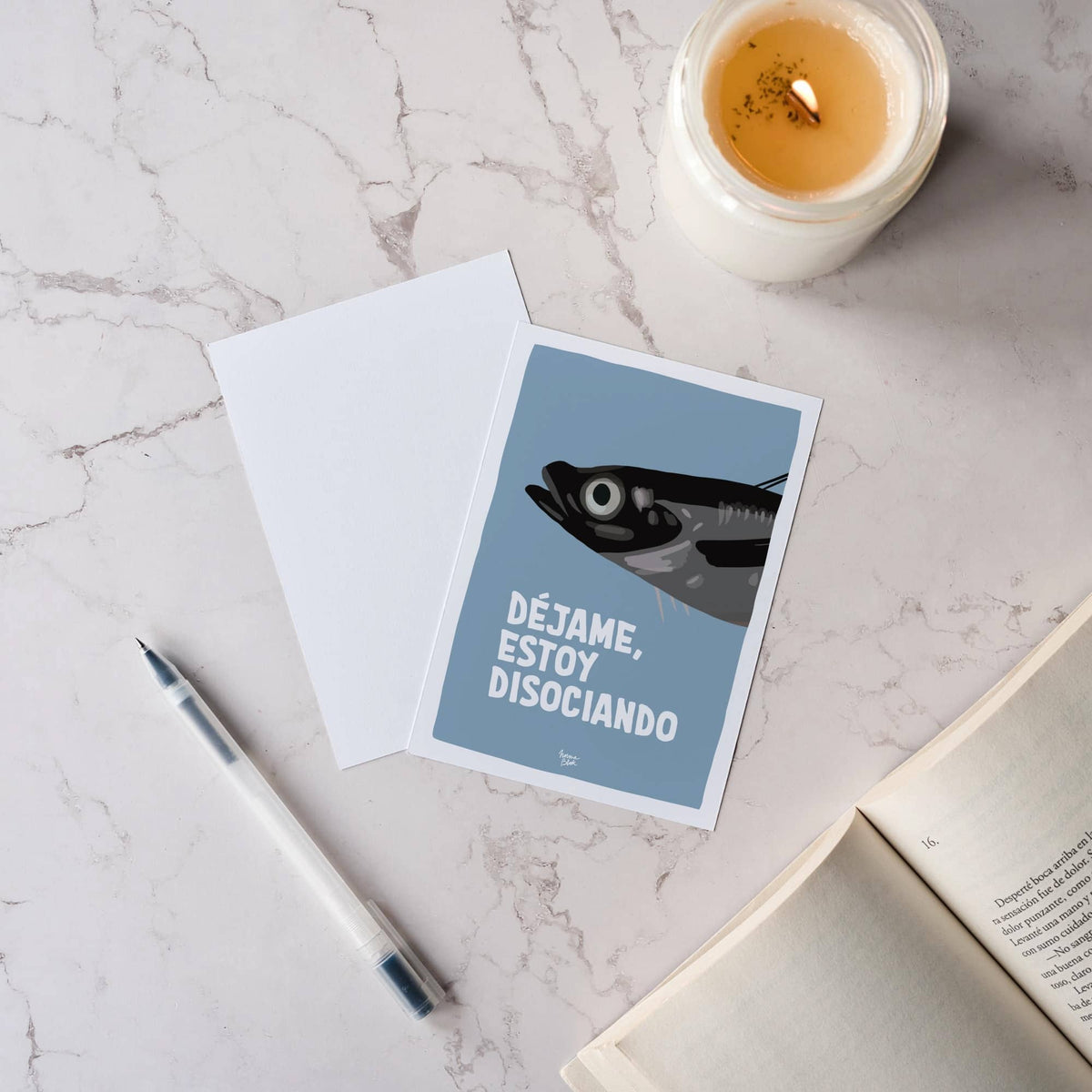 Vista cenital o flat lay de dos postales con ilustración de sardina sobre una mesa de mármol, mostrando el diseño frontal y la parte trasera blanca.