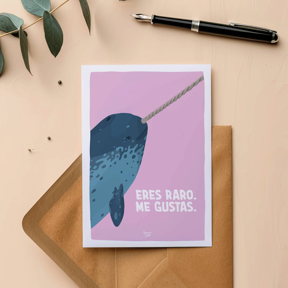 Postal ilustrada con un narval y texto gracioso colocada encima de un sobre de papel.
