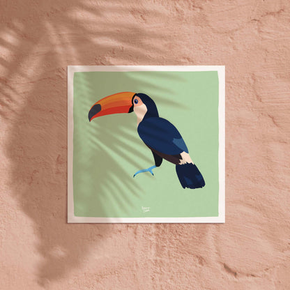 La lámina del tucán en formato cuadrado expuesta sobre una pared de color coral claro suave. El contraste entre la ilustración del pájaro tropical y el fondo cálido coral ofrece una idea decorativa alegre, moderna y de gran impacto para cualquier pared en un espacio infantil.