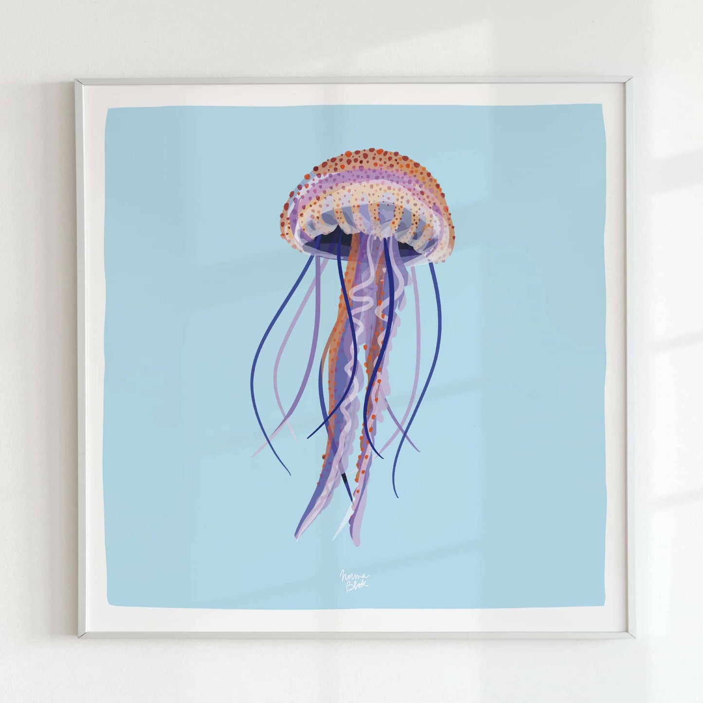 A minimalist shot of the square-format jellyfish print in a sleek white frame, mounted on a white wall. The monochromatic framing highlights the artwork’s transparency and colorful detail without any distractions.