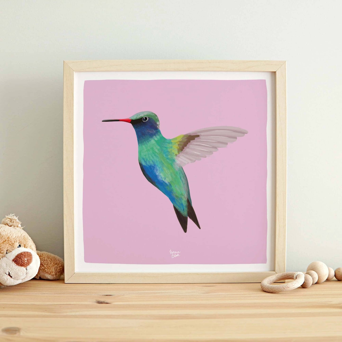 The hummingbird digital illustration adapted into a square format layout, framed and hanging on a wall in a cheerful children's bedroom. The clean white border and balanced composition add a contemporary touch to the room's playful atmosphere.