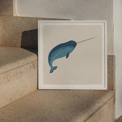 The square-format narwhal print in a frame, stylishly resting on marble stairs, showing a sophisticated and modern way to display art.