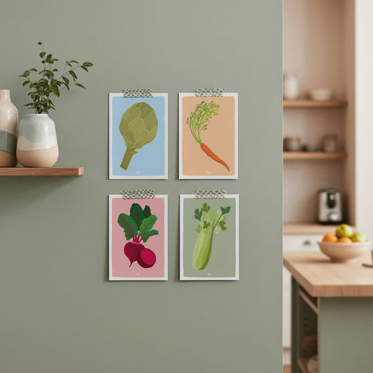 Las cuatro postales de verduras pegadas con washitape en una pared de cocina de color verde salvia, mostrando una forma creativa y desenfadada de decorar un rincón.