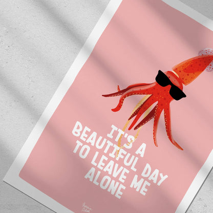Close-up top-down flat lay focusing on the sunglasses-wearing squid against a salmon-pink background in a Normablok art print.