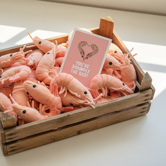 Rustic wooden fishmonger crate filled with plush shrimp stuffed animals, featuring the 'You are shrimply the best' mini art print by normablok.